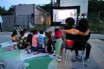 Kinder sitzen vor einer Kinoleinwand, Summer School im Rahmen des Projekts Lunik CoLab