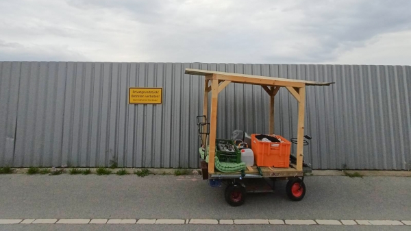 A wooden cart in front of a metal construction
                                          site fence